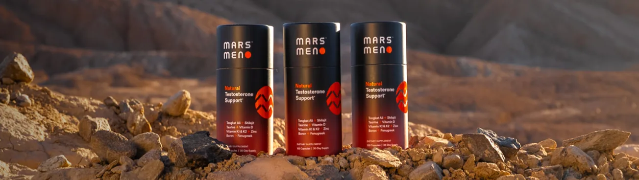Three bottles of Mars Men Natural Testosterone Support supplements sitting on a rocky, desert-like landscape.