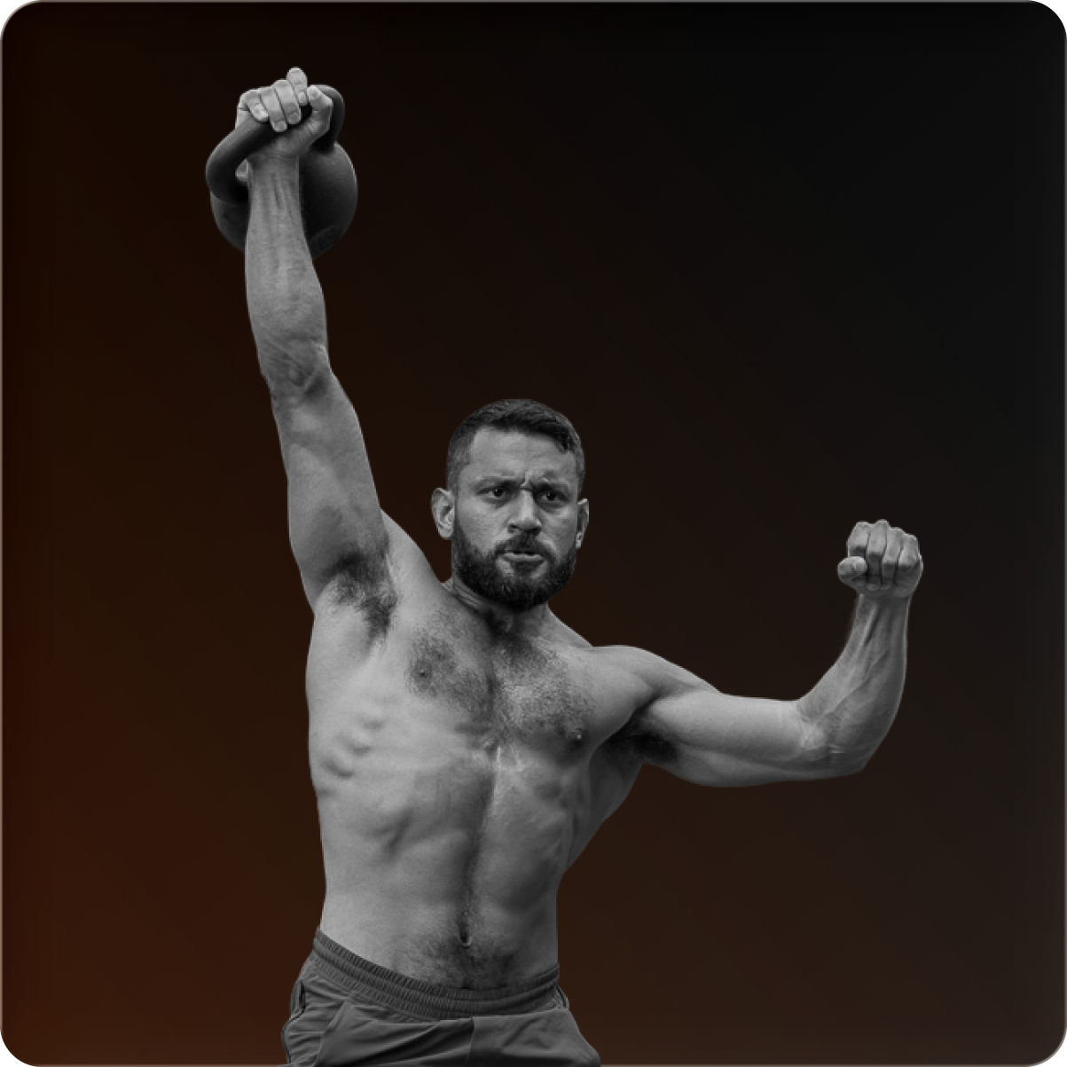 A muscular, shirtless man lifts a kettlebell over his head in black and white.