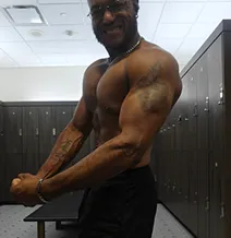 Person flexing muscles in a gym locker room.