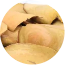A close-up, circular view of light brown wood shavings or pieces of bark.