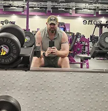 Man taking a selfie in a gym, surrounded by equipment.