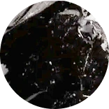 A circular, black and white abstract image of a dark, textured surface with light specks.