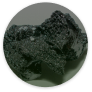 A circular close-up of a dark, porous, crystalline rock or mineral.