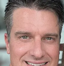 Close-up of a smiling man with short dark hair.