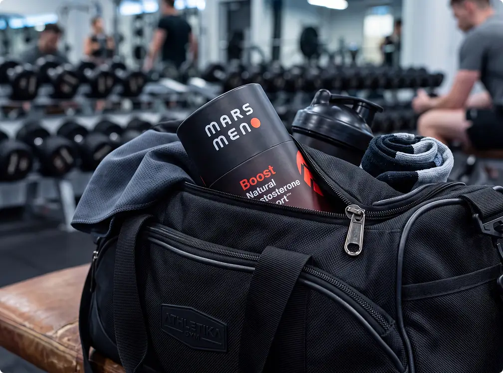 A container of Mars Meno Boost supplement is shown inside an open black gym bag at a gym.