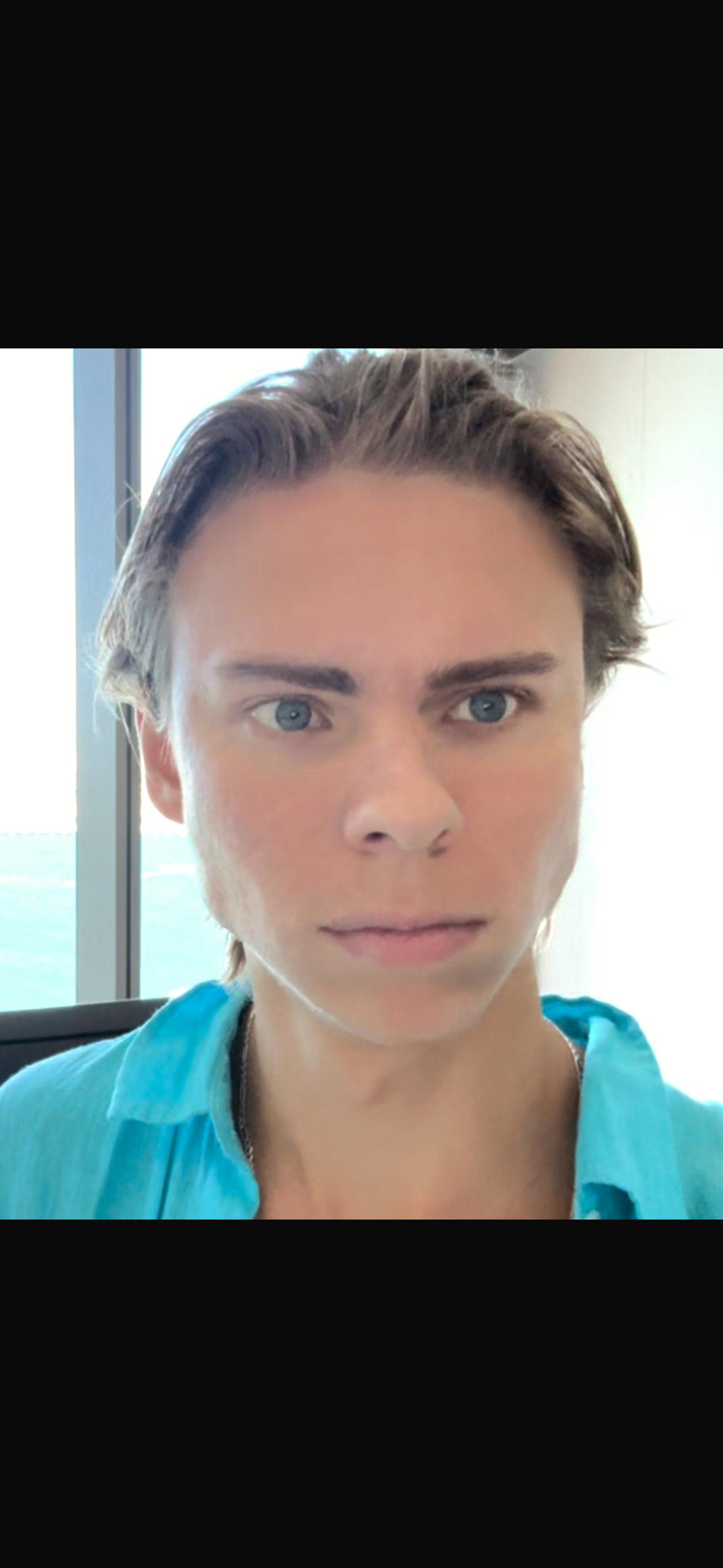 Person with short hair wearing a blue shirt, looking directly at the camera.
