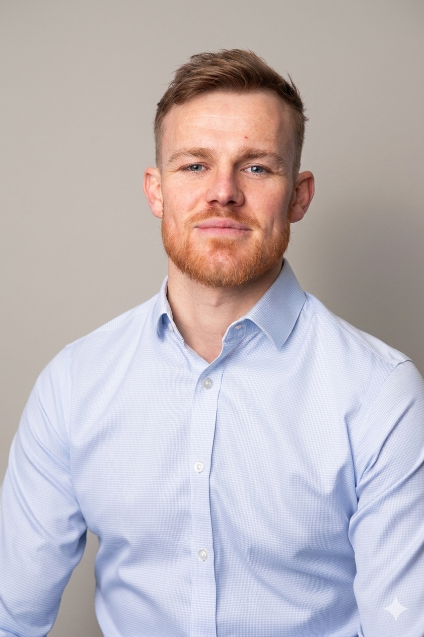 A headshot of a man with reddish-blond hair and a beard, wearing a light blue button-down shirt.