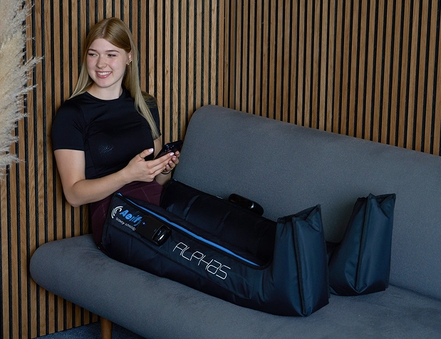 Woman sitting on a couch with a leg compression device.