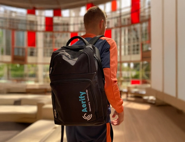 Person with a black backpack in a modern, bright room with red accents.