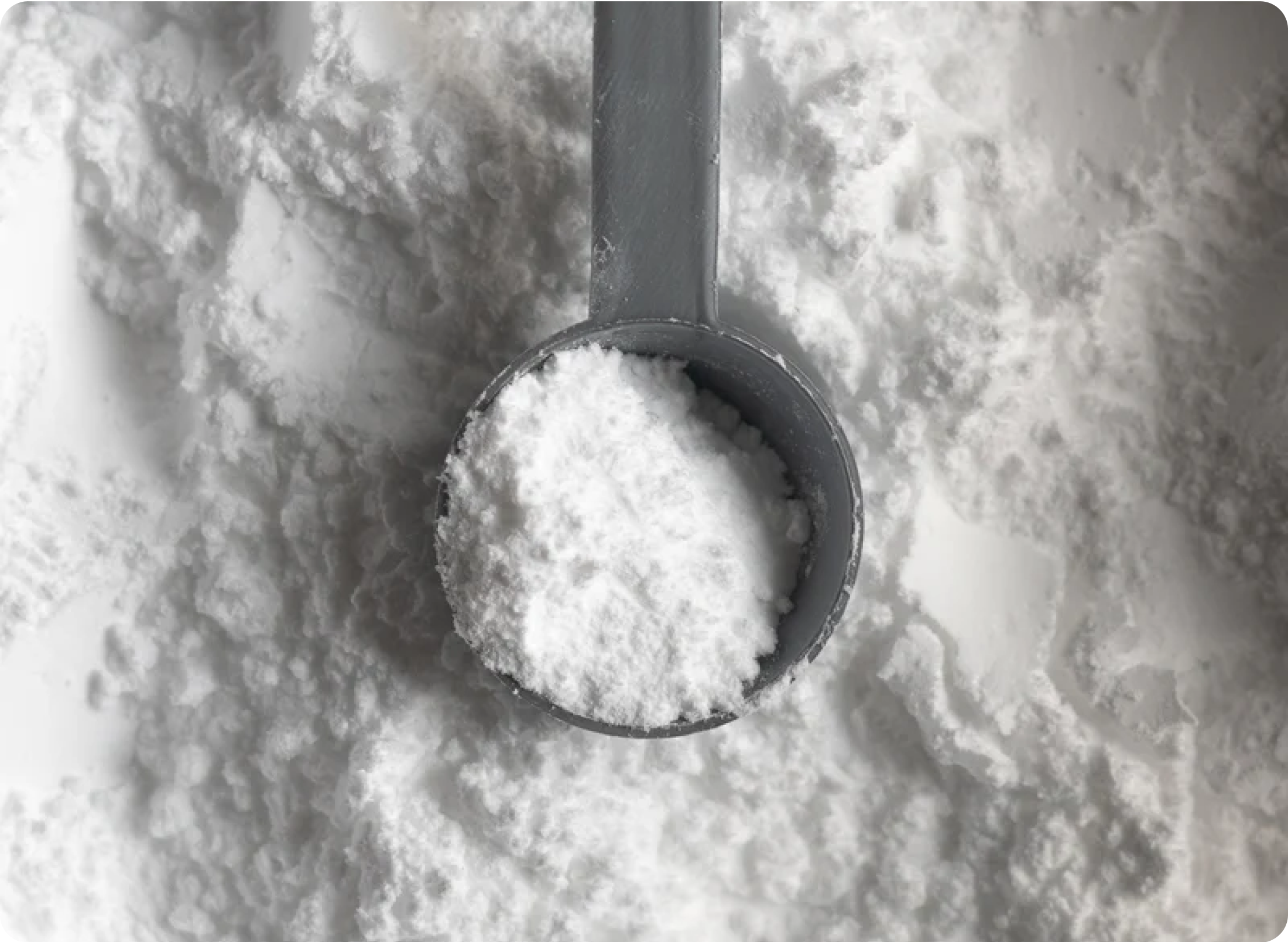 Measuring scoop filled with white powder on a textured surface.