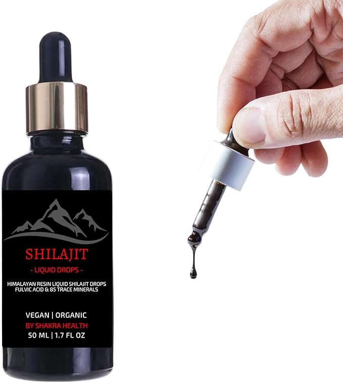 Hand holding dropper with liquid near Shilajit bottle.