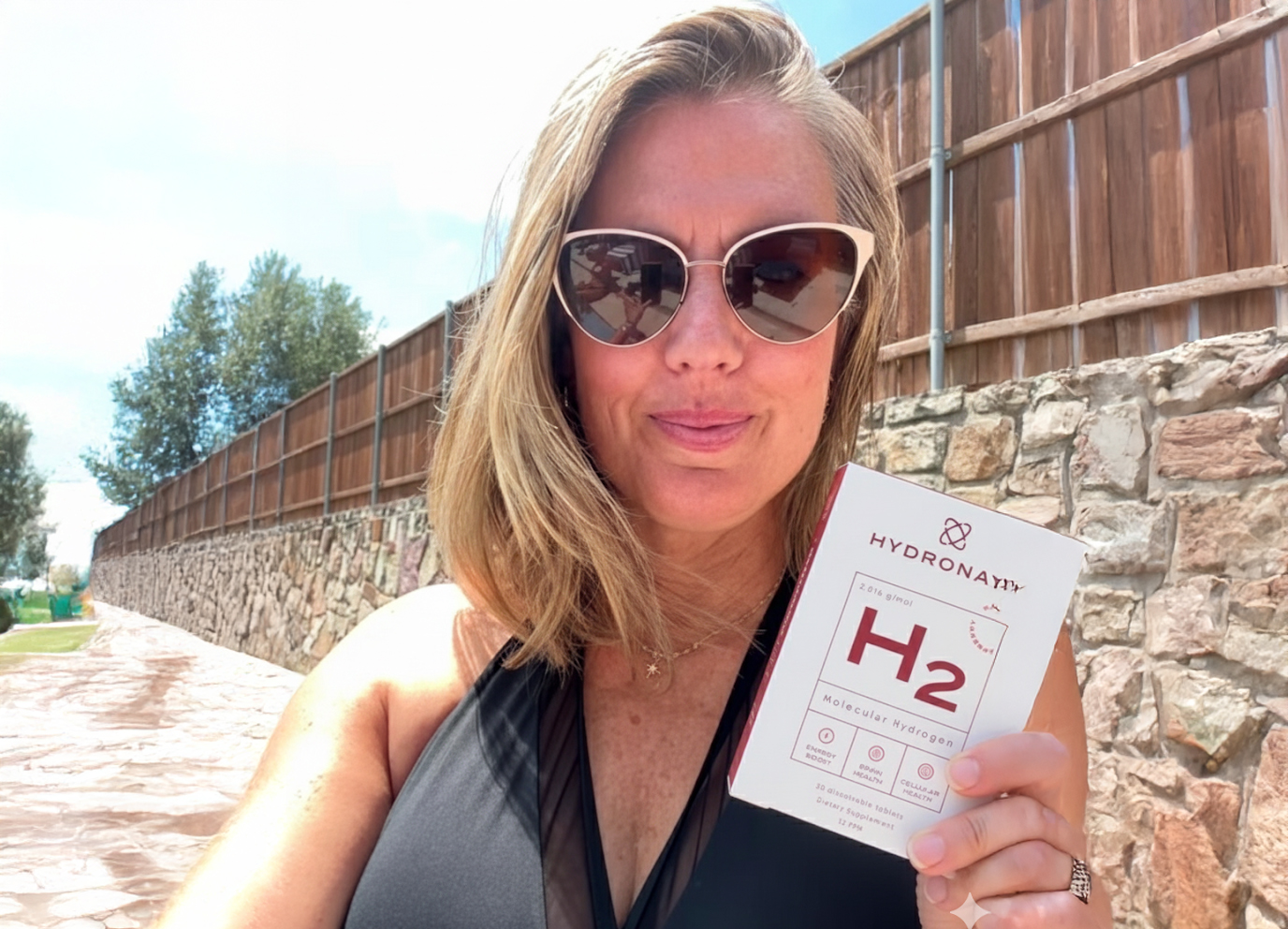 Person in sunglasses holding a box labeled 'Hydronayin H2' in a sunny outdoor setting.