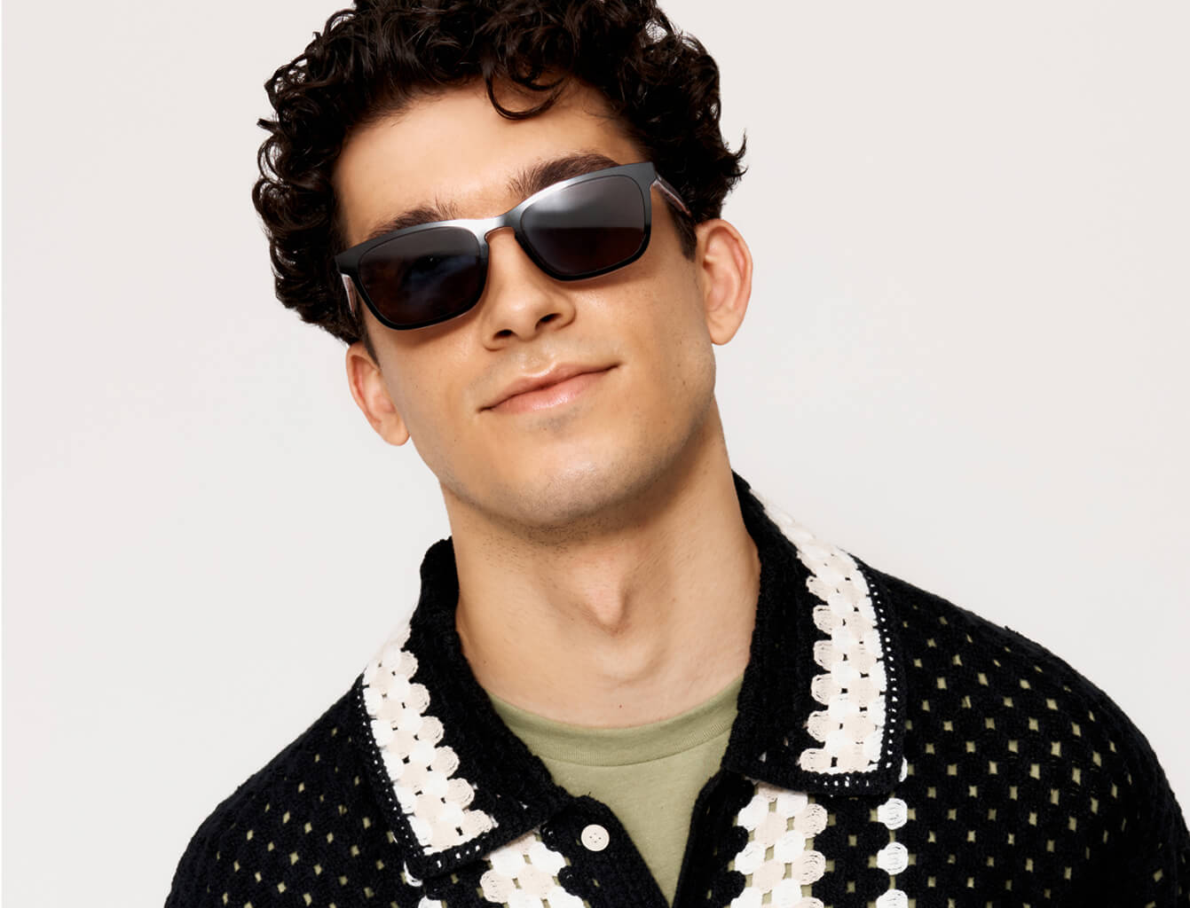 Person wearing sunglasses and a patterned shirt, smiling slightly.