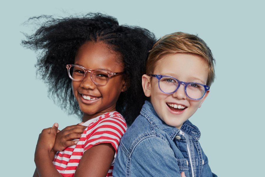 Two smiling children wearing glasses, back-to-back against a light blue background.