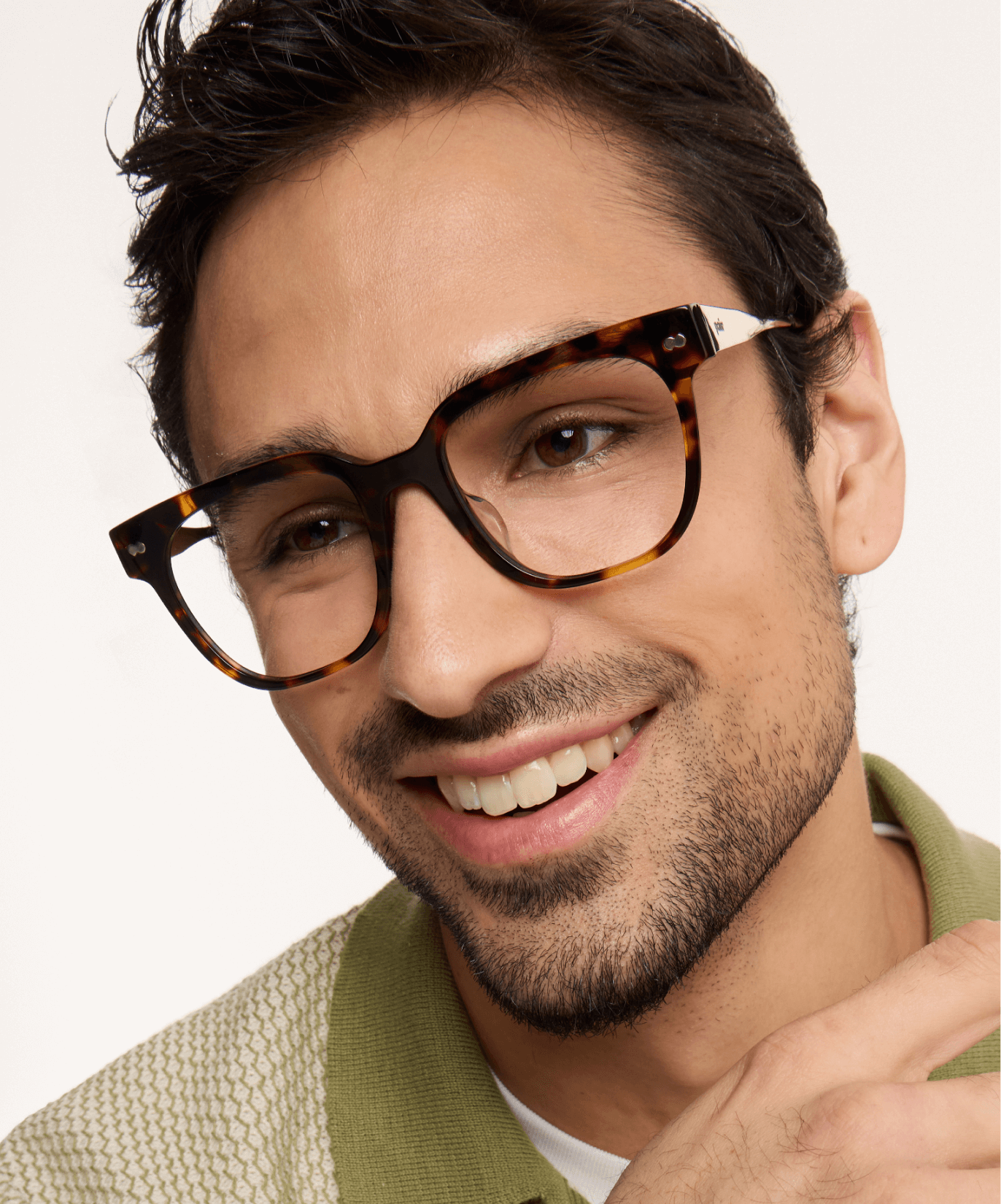 Smiling man wearing tortoiseshell glasses and a green collared shirt.