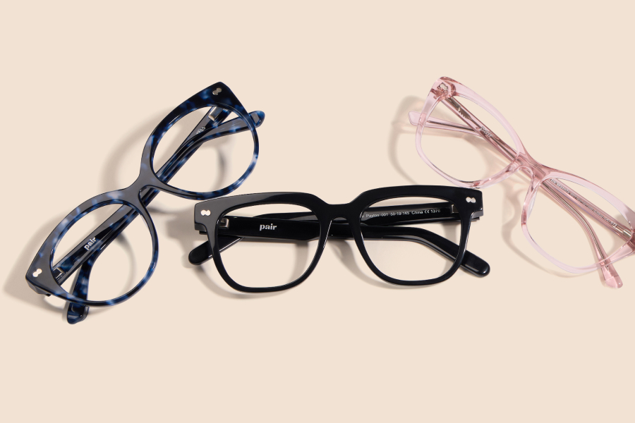 Three pairs of eyeglasses on a beige background.