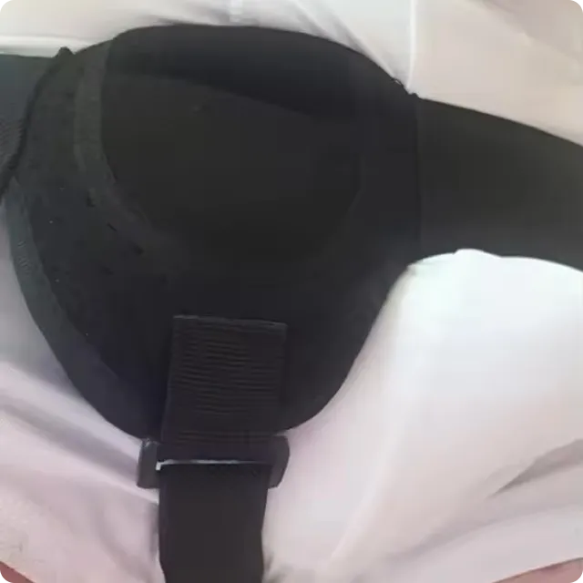 A close-up of a black padded arm sling with an adjustable strap and buckle on a white surface.