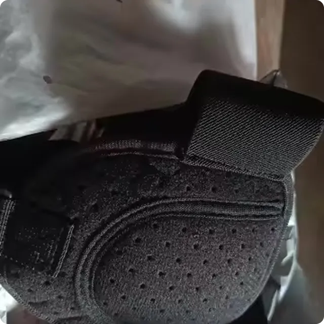 A close-up of a black, perforated support brace with adjustable straps inside its packaging.