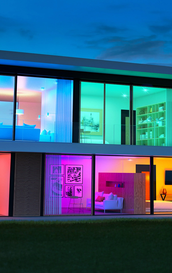 Modern house with colorful interior lighting visible through large windows.