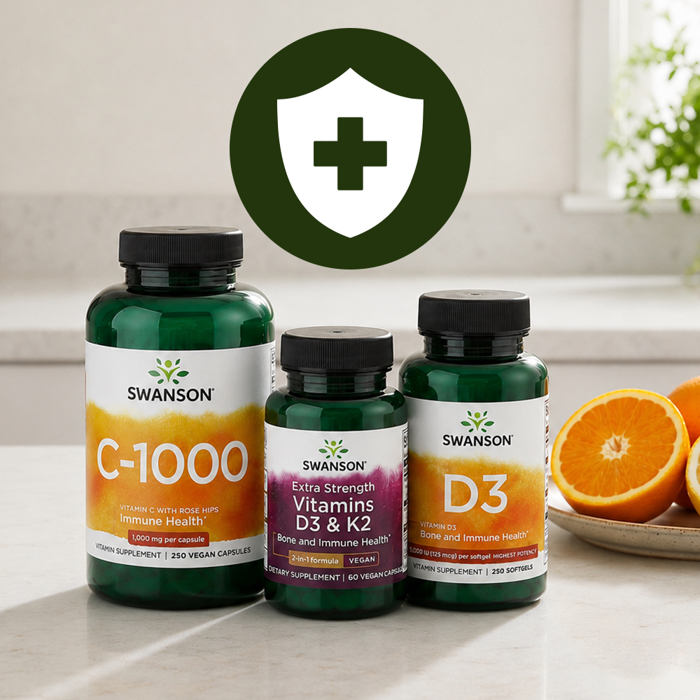 Three Swanson vitamin bottles—C-1000, D3 & K2, and D3—on a kitchen counter beside oranges, with a green shield and cross icon.