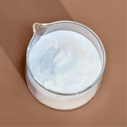 Glass container filled with white powder on a brown surface.