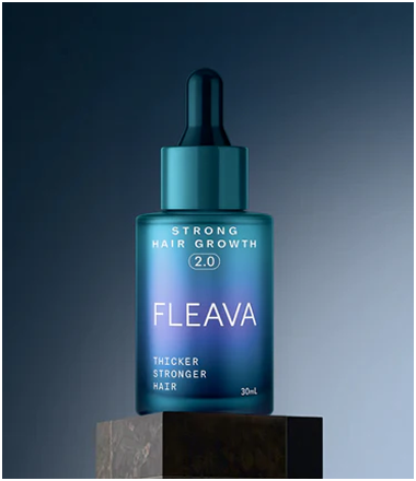 A bottle of Fleava Strong Hair Growth 2.0 serum resting on a dark stone pedestal.