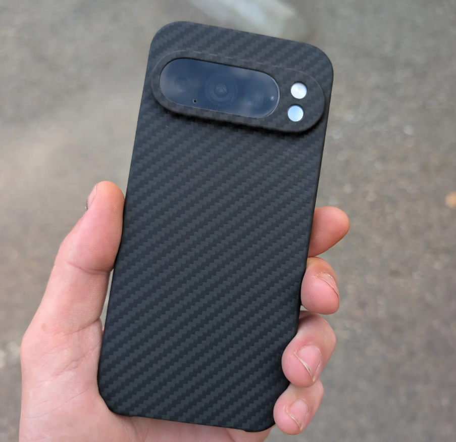 Hand holding a carbon fiber phone case with a camera cutout.