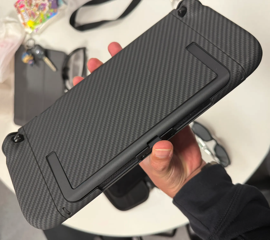 Hand holding a device with a carbon fiber pattern cover.