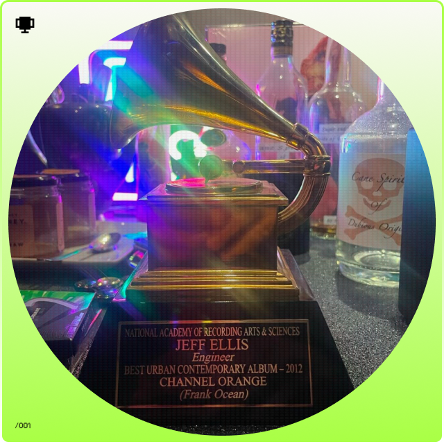 Grammy award trophy with colorful lights and bottles in the background.