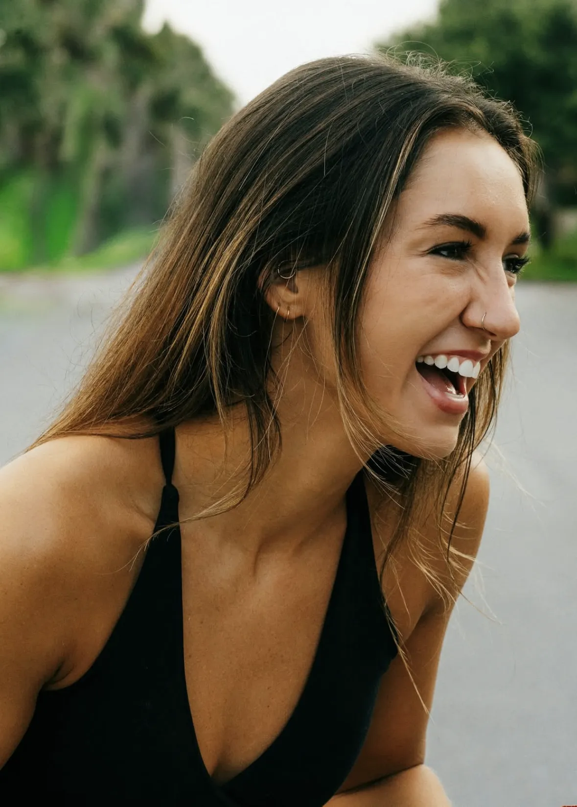 Woman smiling outdoors with trees in the background.