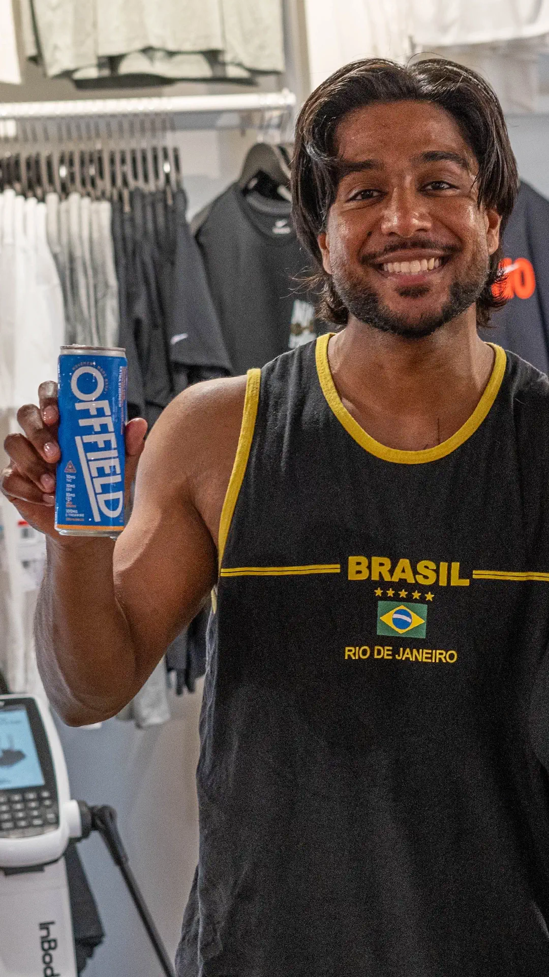 Person smiling, holding a blue can of OFFFIELD, wearing a 'Brasil Rio de Janeiro' shirt.