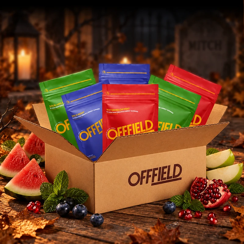 A cardboard box of Offfield energy gummies pouches surrounded by fresh fruit in a spooky, autumn setting.