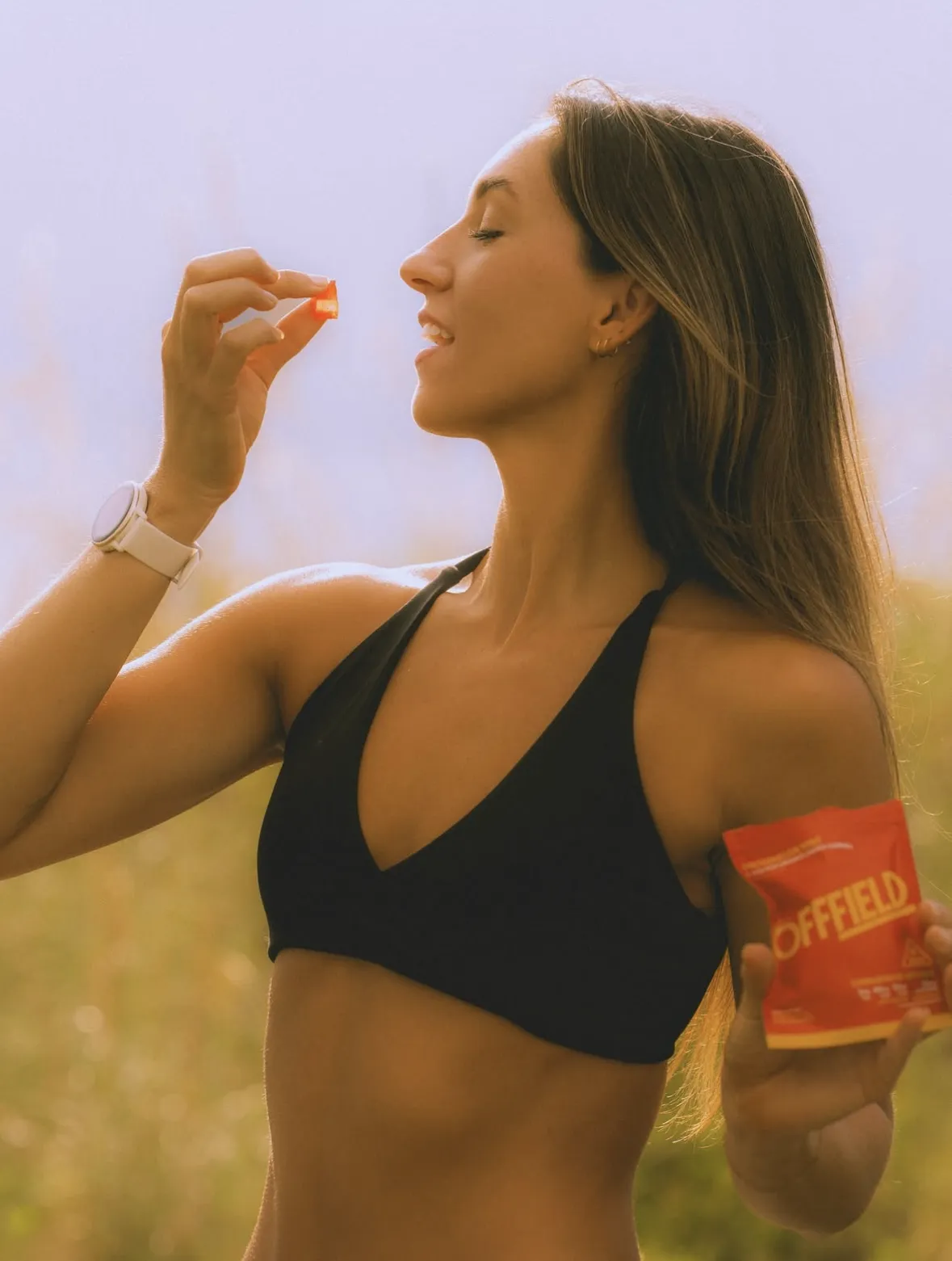 Person in a sports bra holding a snack, about to eat a piece.