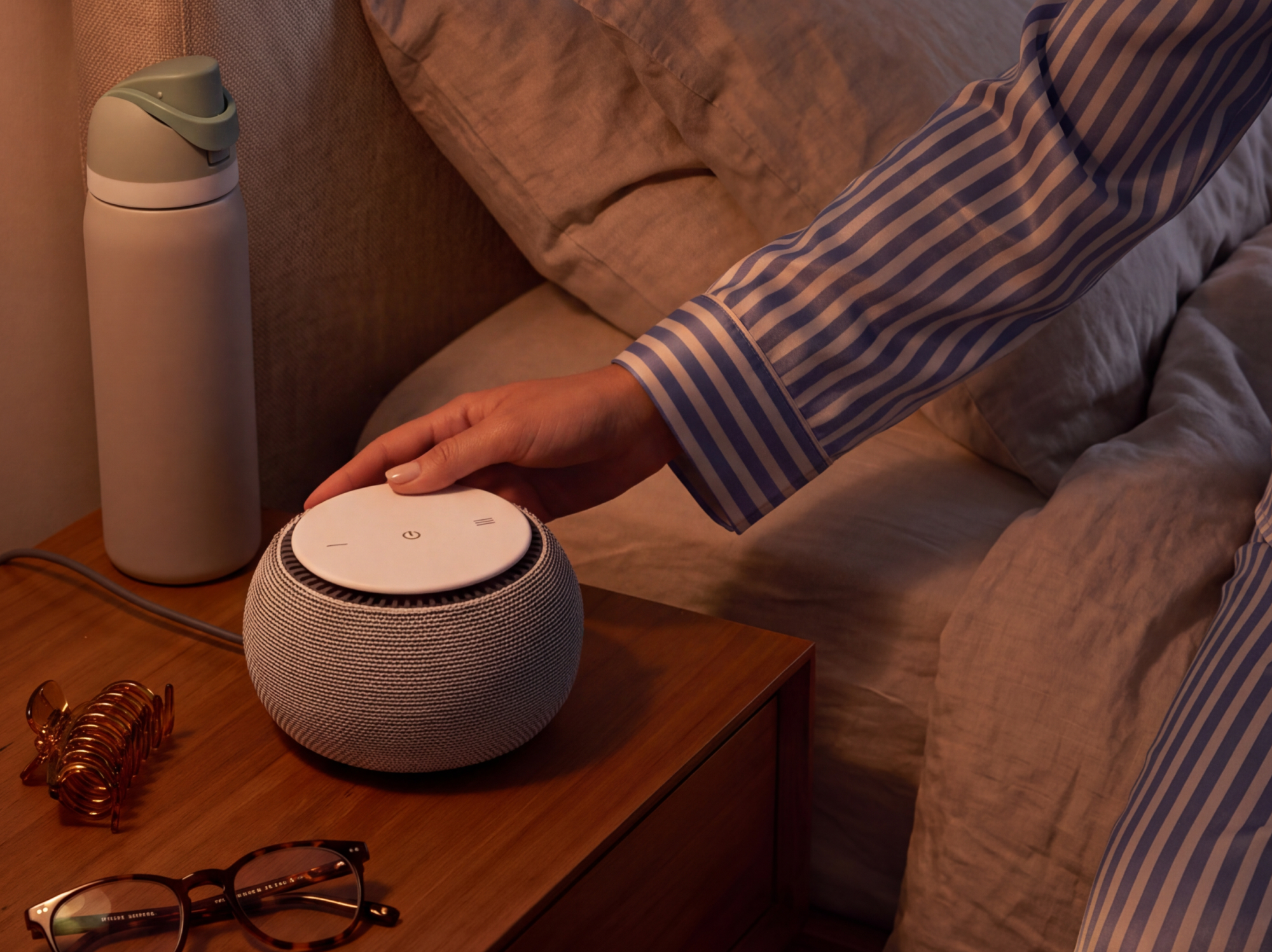 A woman's hand places snooz original on her nightstand.