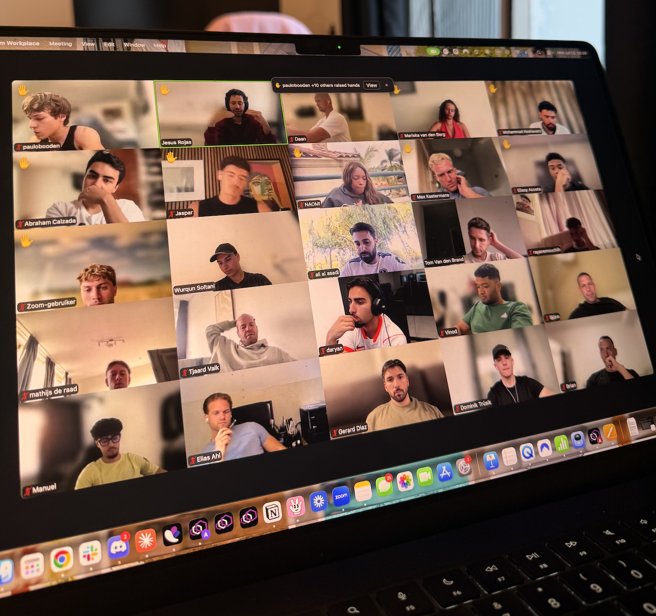 A laptop screen showing a large video conference call with many participants in a grid view.