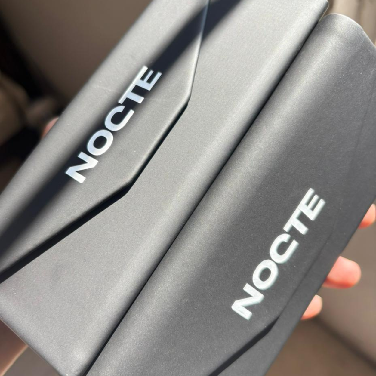 A close-up shot of two black cases with the word 'NOCTE' printed in white letters.
