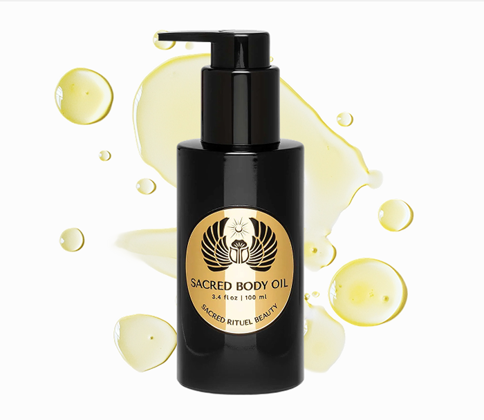 Black bottle of Sacred Body Oil with golden label and oil droplets.