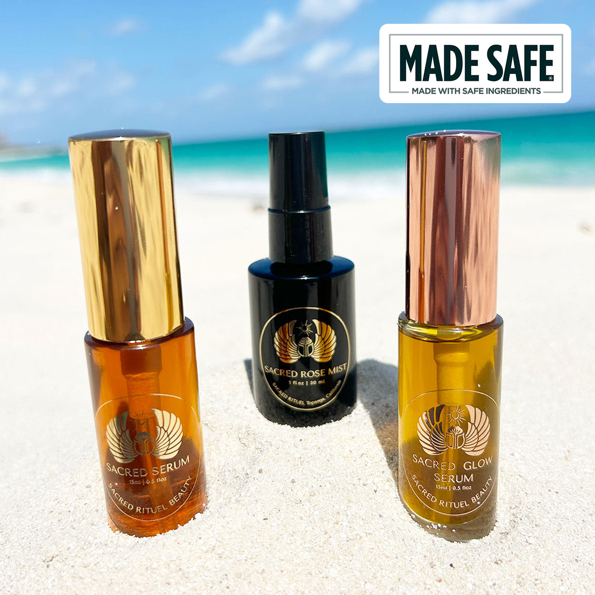 Three skincare bottles on sand with ocean and blue sky background.
