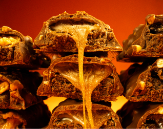 A close-up of stacked chocolate candy bars with caramel oozing from the center.
