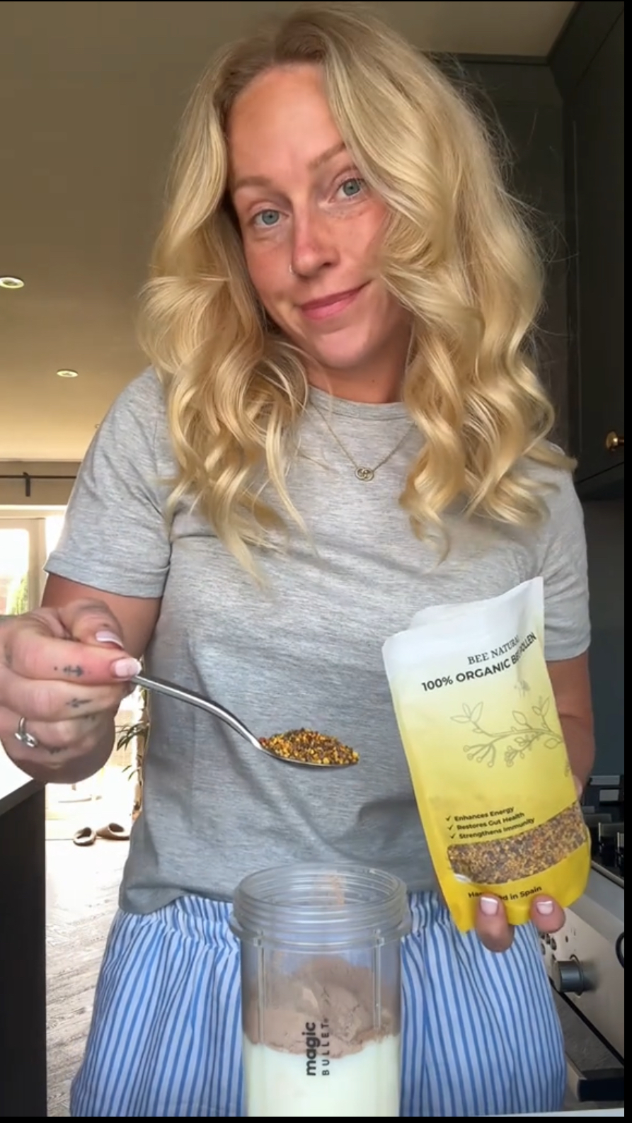 Person adding bee pollen to a blender cup with milk and powder.