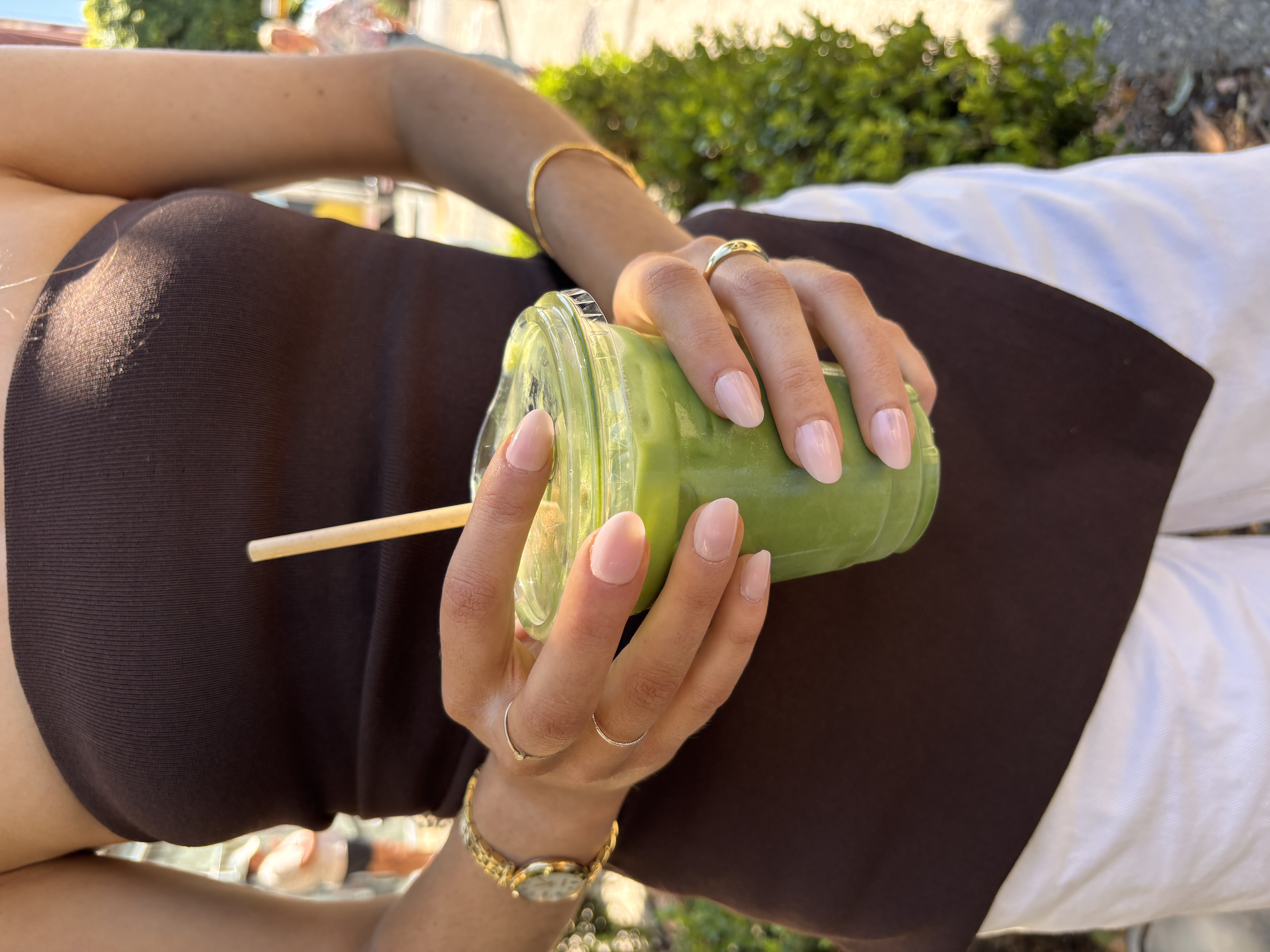 A hand with a light pink French manicure, background showing a room.