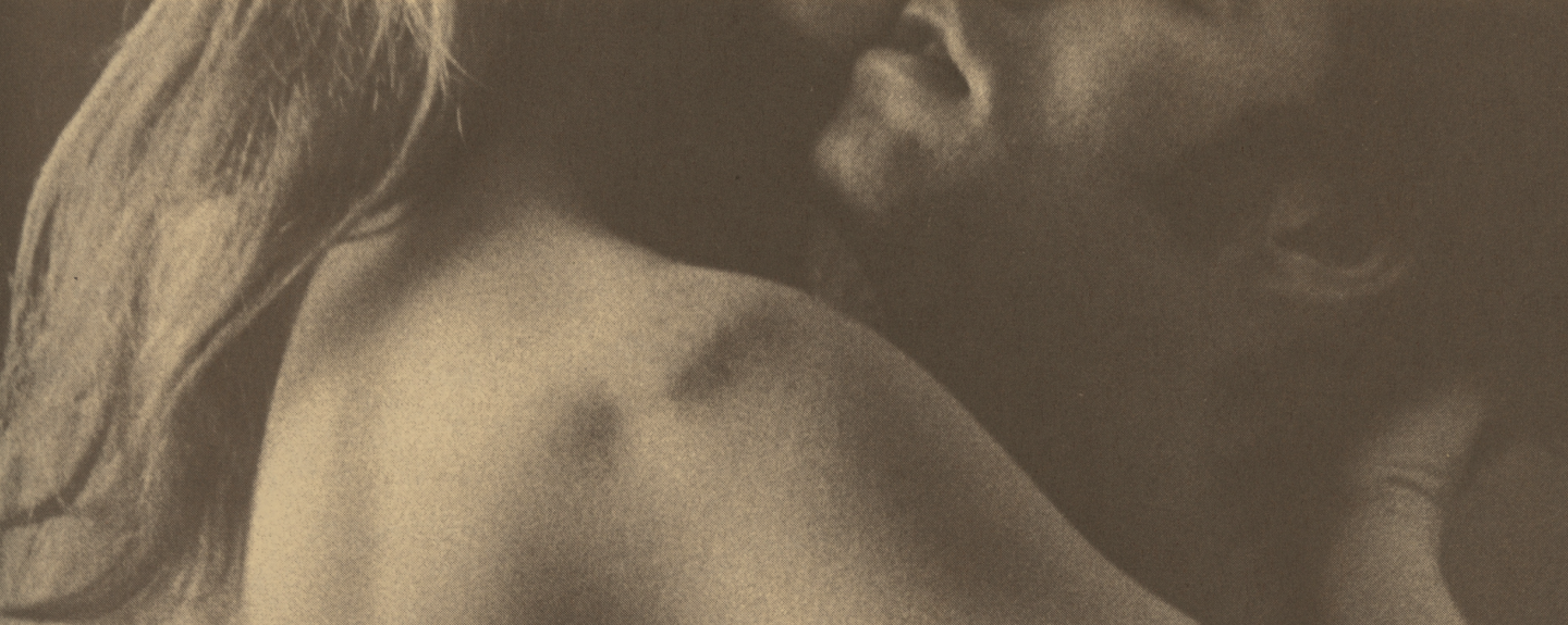 A sepia-toned, close-up photograph of two people in an intimate embrace.