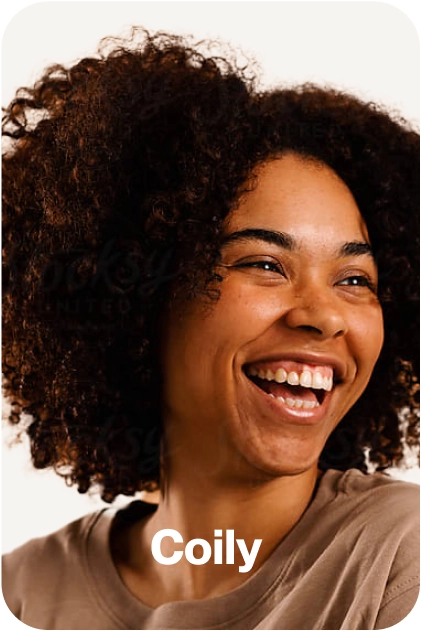 Smiling person with curly hair, wearing a beige shirt.