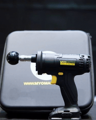 Black massage gun with a round attachment in front of a branded case.