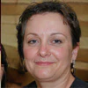 Portrait of a person with short hair smiling slightly.