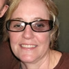 A person wearing glasses and smiling, close-up view.