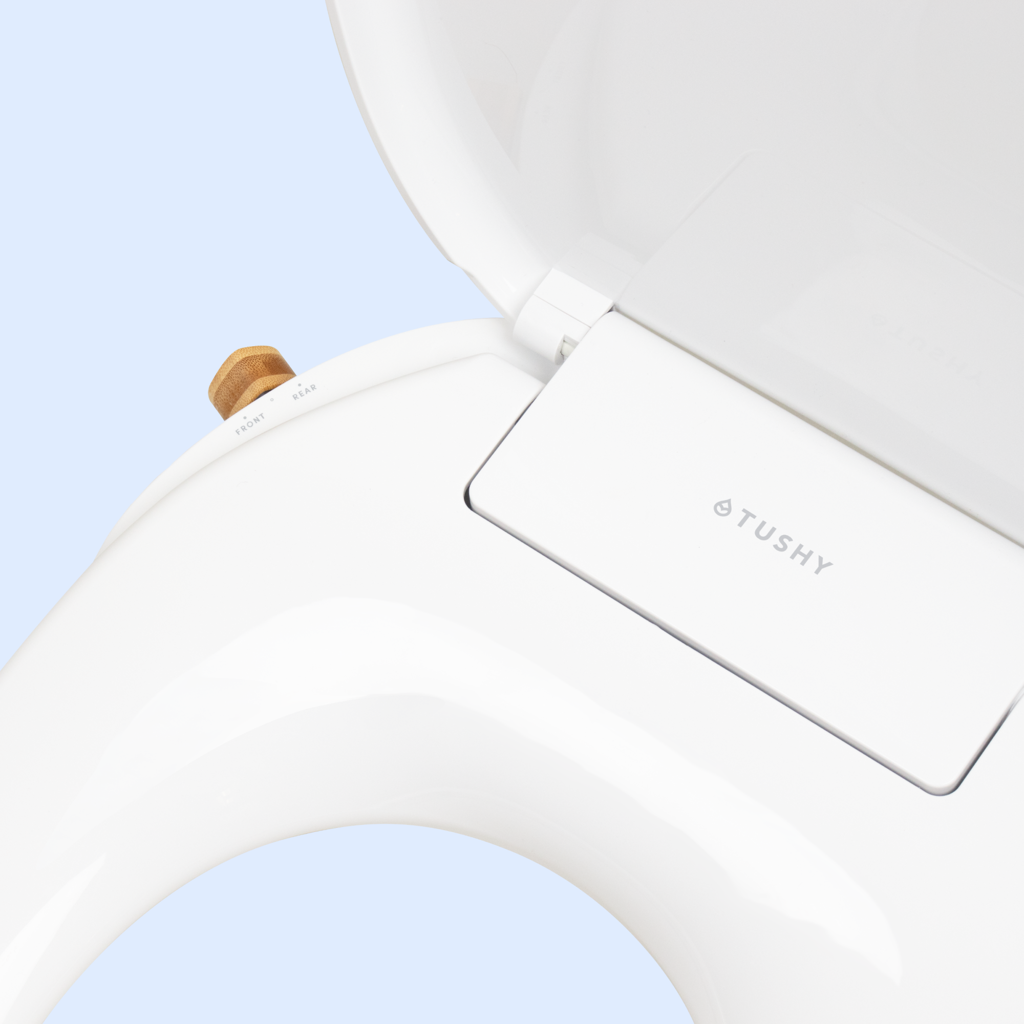 Close-up of a white toilet seat with 'TUSHY' branding.