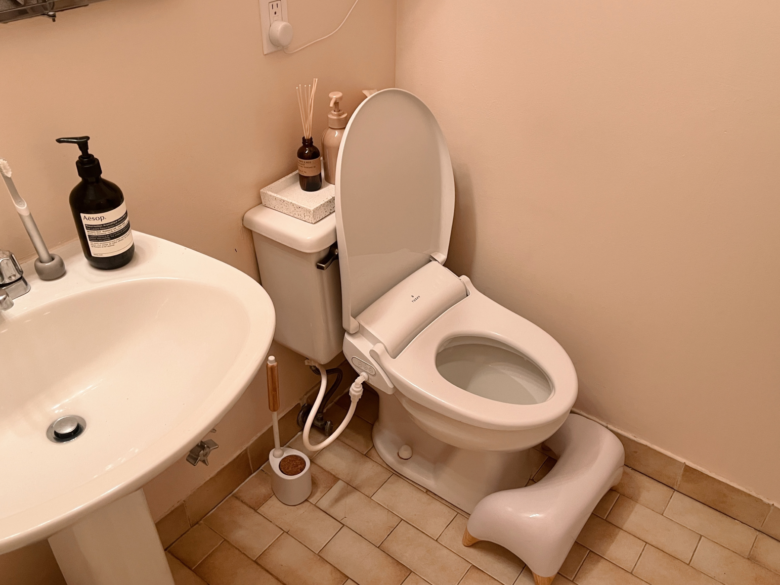 Bathroom with a toilet, sink, and soap dispenser.