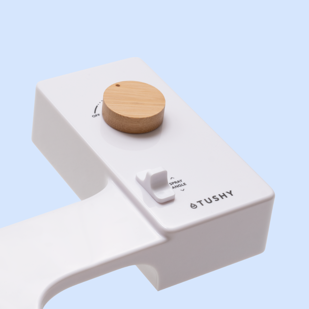 White bidet attachment with a wooden knob and spray angle control.