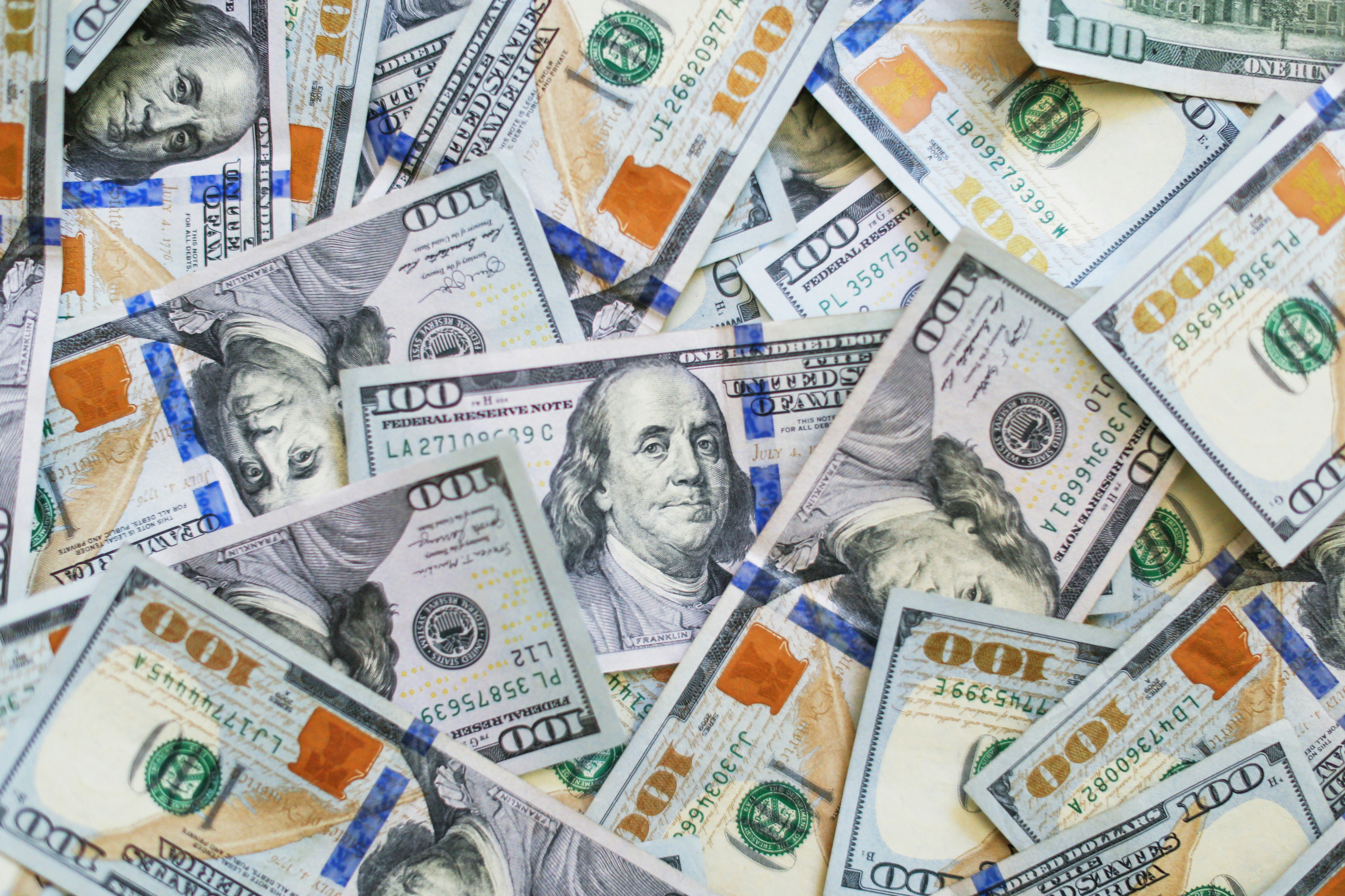 A pile of scattered U.S. one hundred dollar bills.